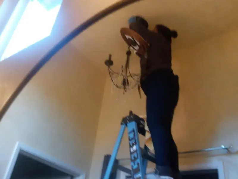 Electrician installing a chandelier in a Park residence
